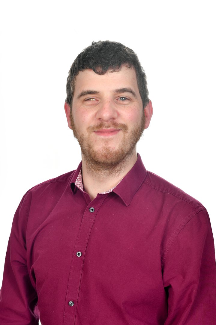 Sean Randall smiling in a burgundy shirt against a white background.